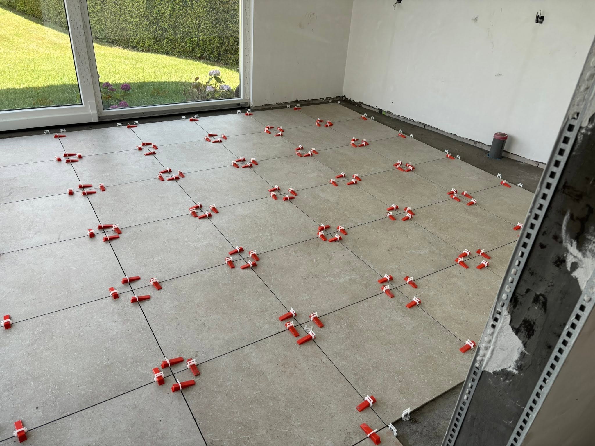 Dalles de carrelage gris clair avec clips de nivellement rouges et blancs
