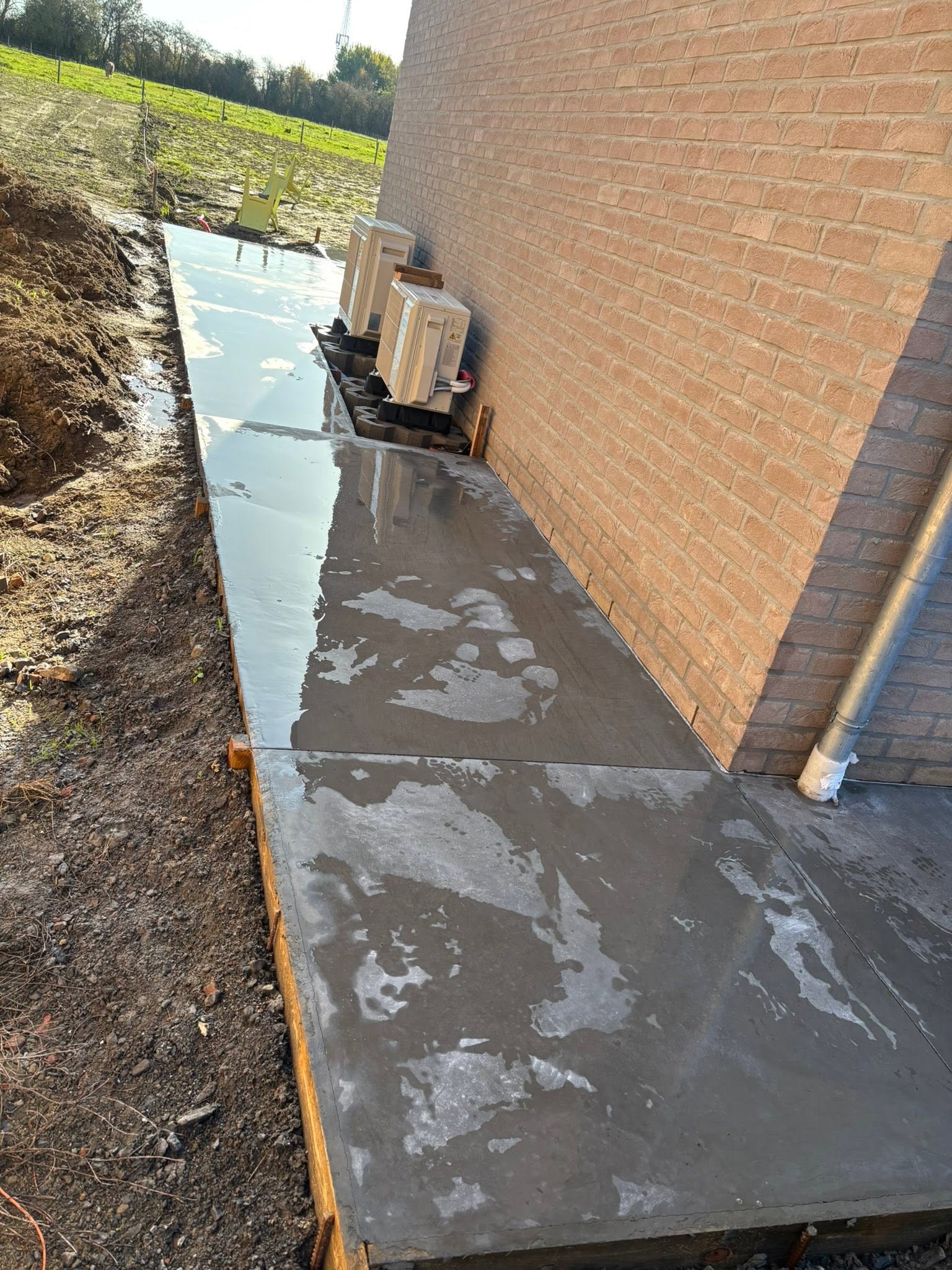 Dalle béton fraîche avec coffrage le long d'une façade en briques